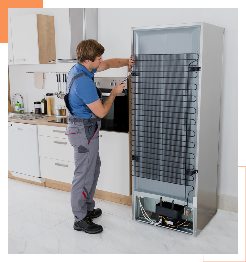 Appliance repair technician servicing refrigerator condenser coils on back of unit.