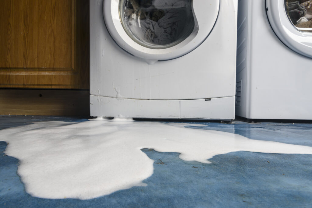 Laundry machine leaking water and soap onto the floor.